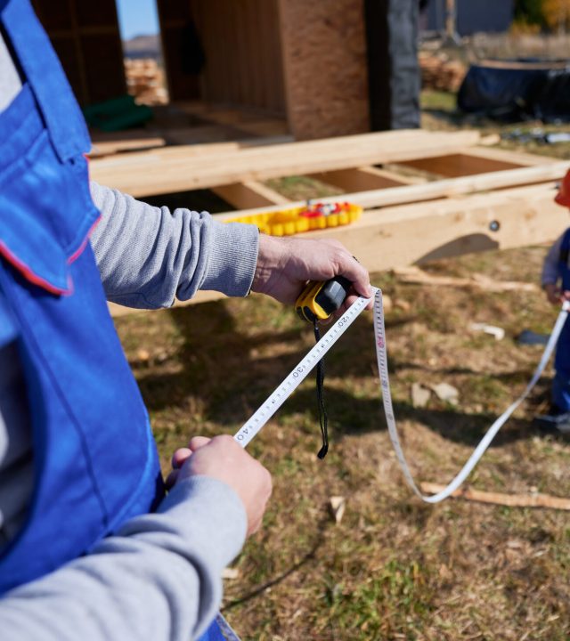 Father with toddler son building wooden frame house.